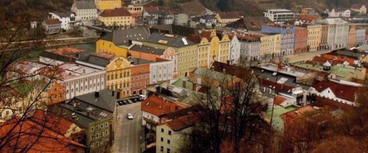 A town with colorful buildings and a hilly landscape in the background.