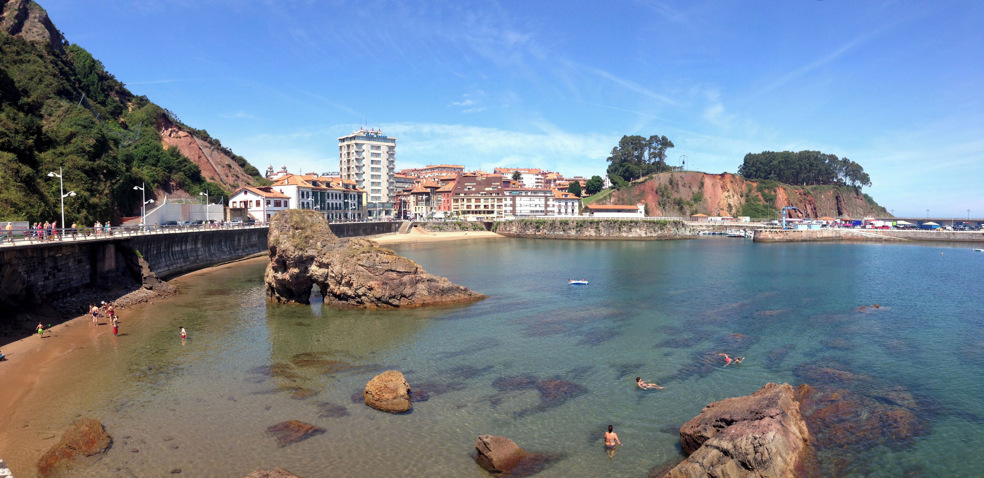 A coastal town with clear waters, rocky outcrops, and buildings along the shore.