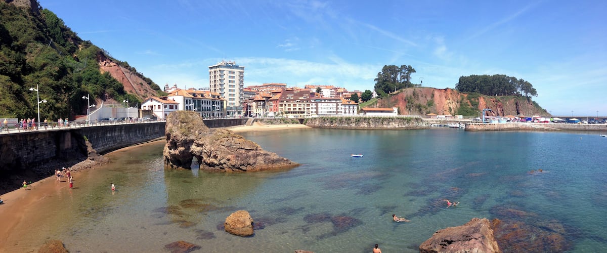 A coastal town with clear waters, rocky outcrops, and buildings along the shore.