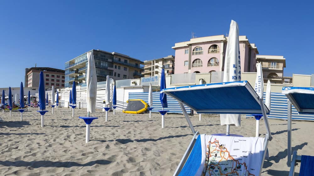 A beach with blue and white sun loungers, umbrellas, and a map of Serbia.