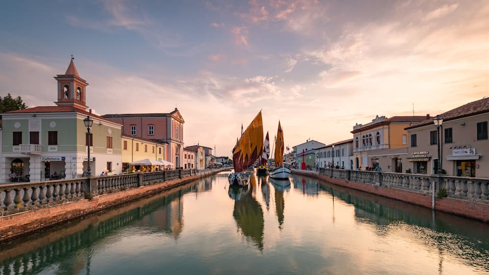A canal with boats, historic buildings, and a clock tower.