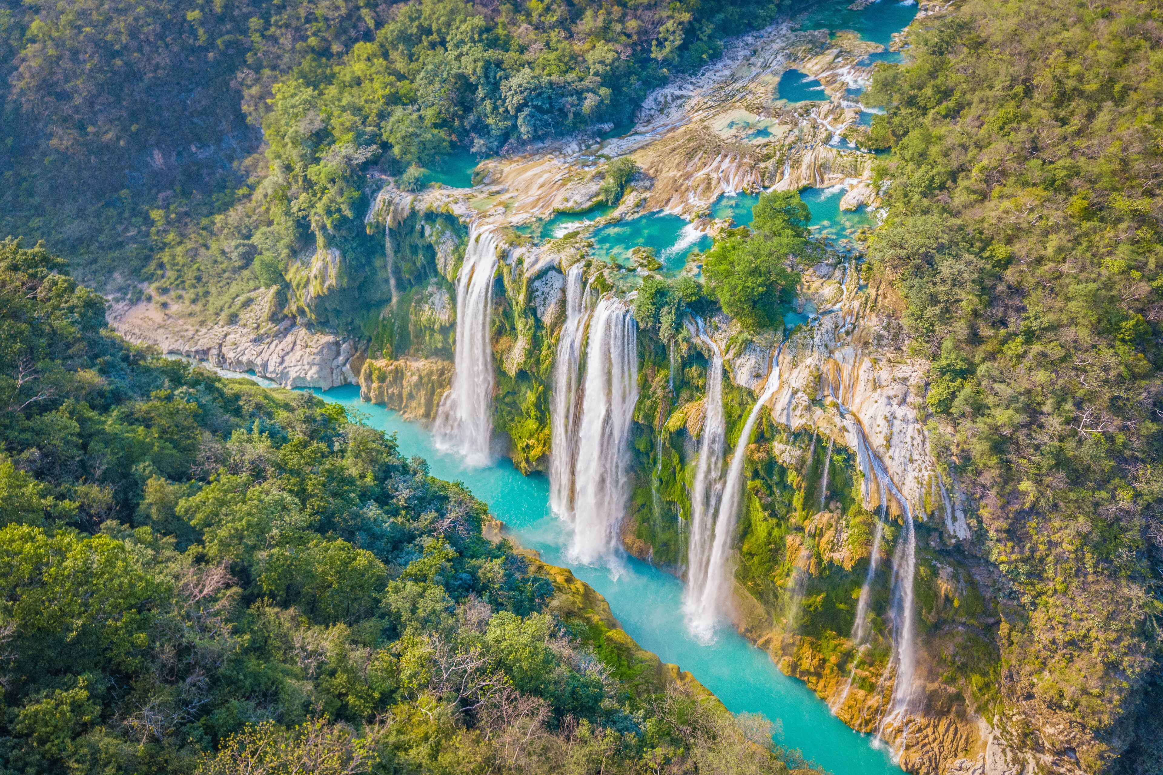 A waterfall cascading down a rocky cliff surrounded by dense green forest.