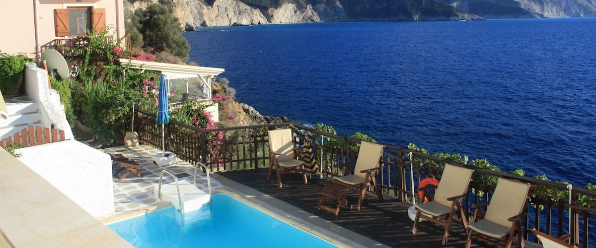 A poolside with a view of the sea and mountains.