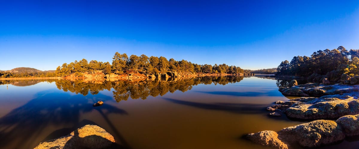 A calm lake surrounded by rocky shores and dense forest.