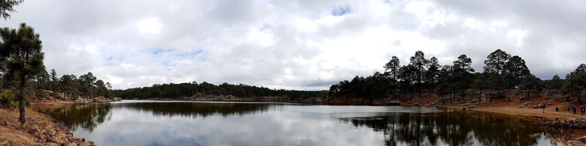A calm lake surrounded by rocky terrain and dense forest.
