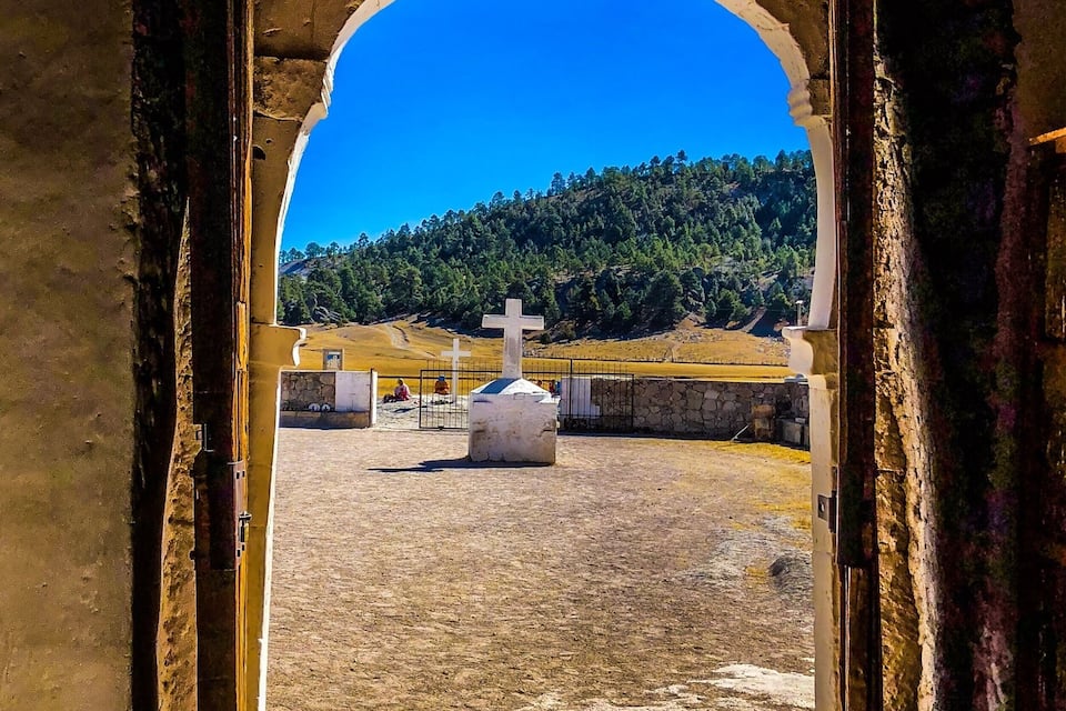 Un arco de entrada que da a un cementerio con una cruz en el centro.