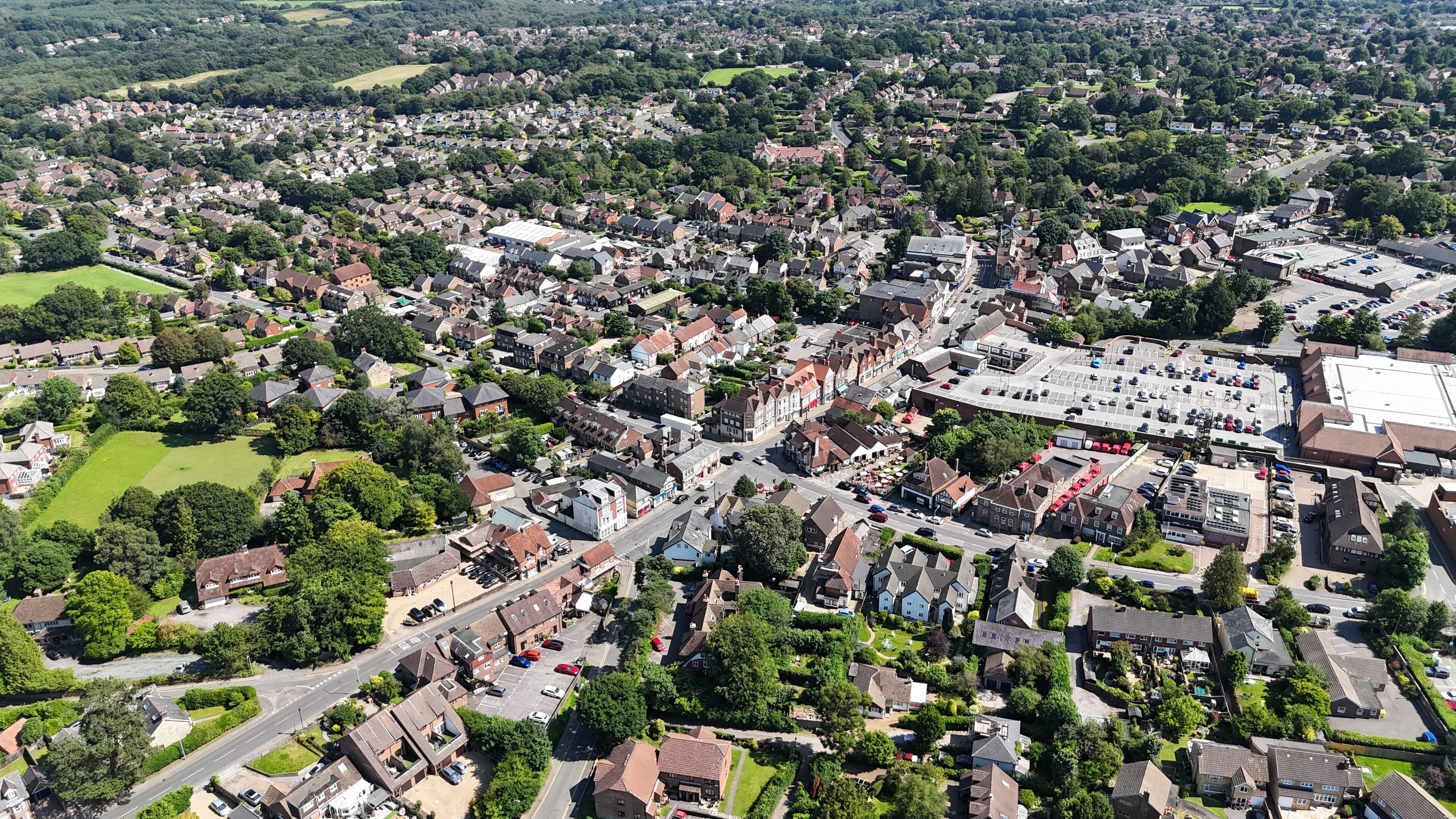 An aerial view of a densely populated residential area with houses, roads, and a large industrial building.