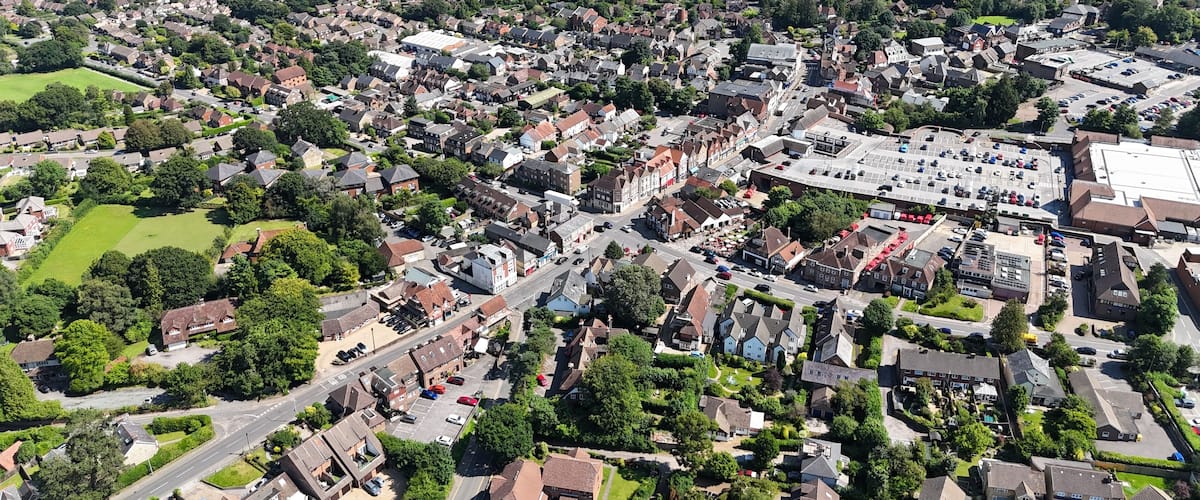 An aerial view of a densely populated residential area with houses, roads, and a large industrial building.