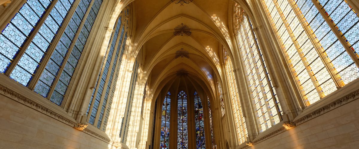A cathedral interior with tall stained glass windows and arched ceilings.