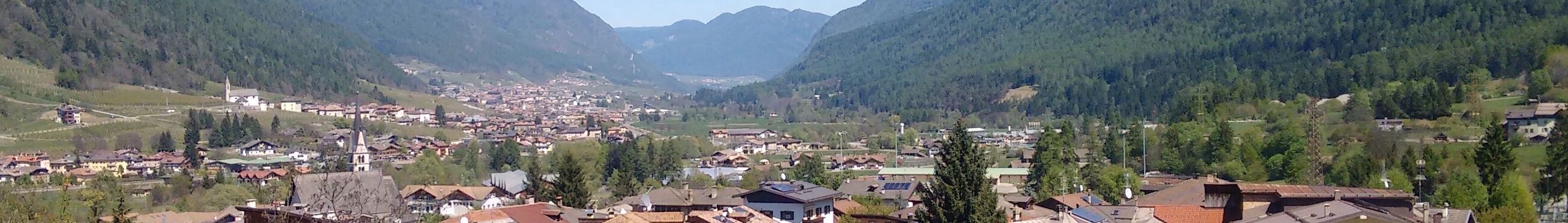 A valley with a town surrounded by mountains and greenery.