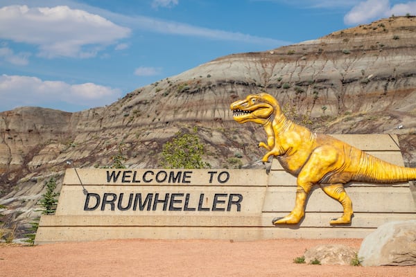 A dinosaur statue and a welcome sign at Drumheller.
