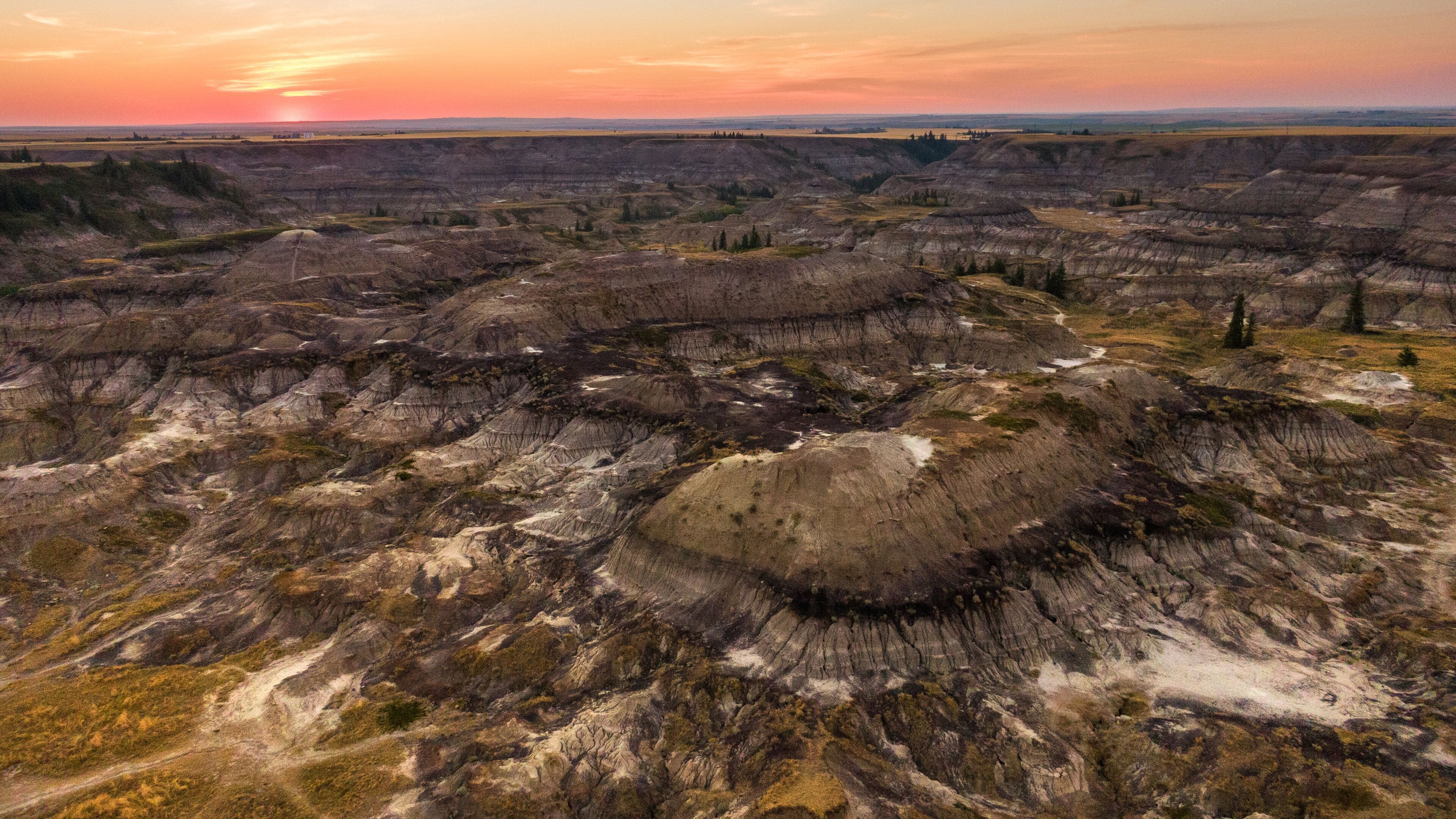 A vast landscape with layered badlands and sparse vegetation.