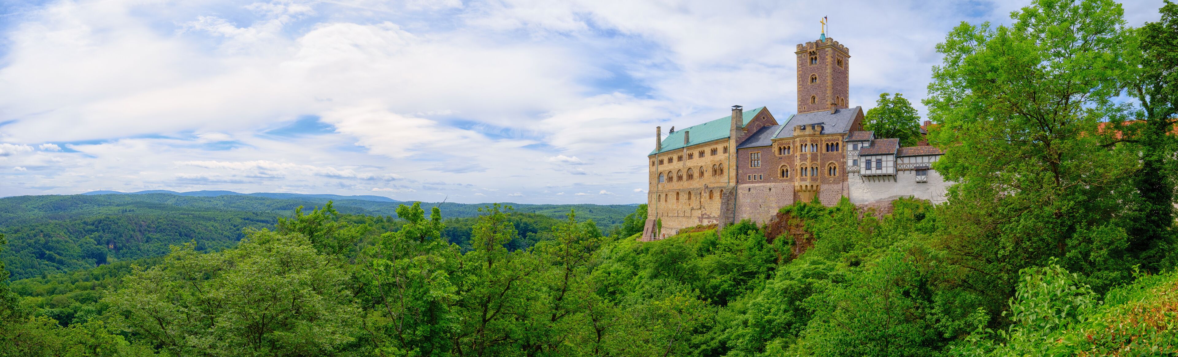 A castle surrounded by lush green forest and hills.