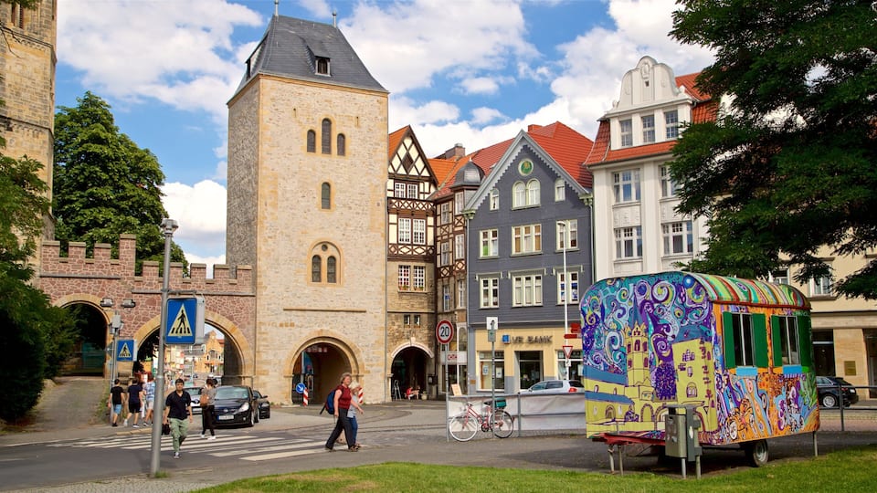 A historic town square with a prominent stone tower, colorful half-timbered buildings, and a vibrant street vendor cart.