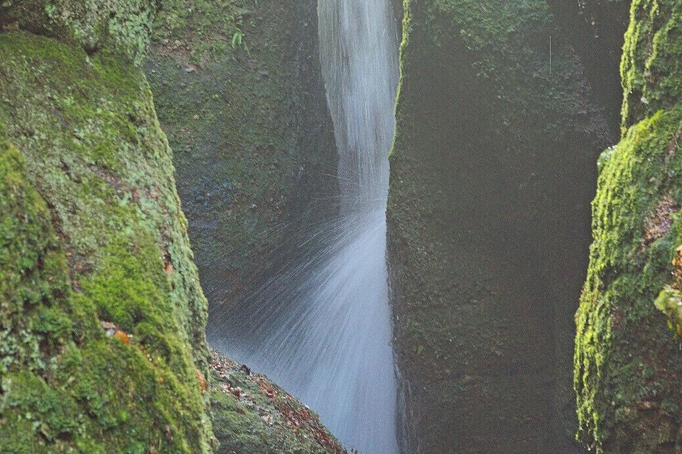 A waterfall cascading down moss-covered rock walls.