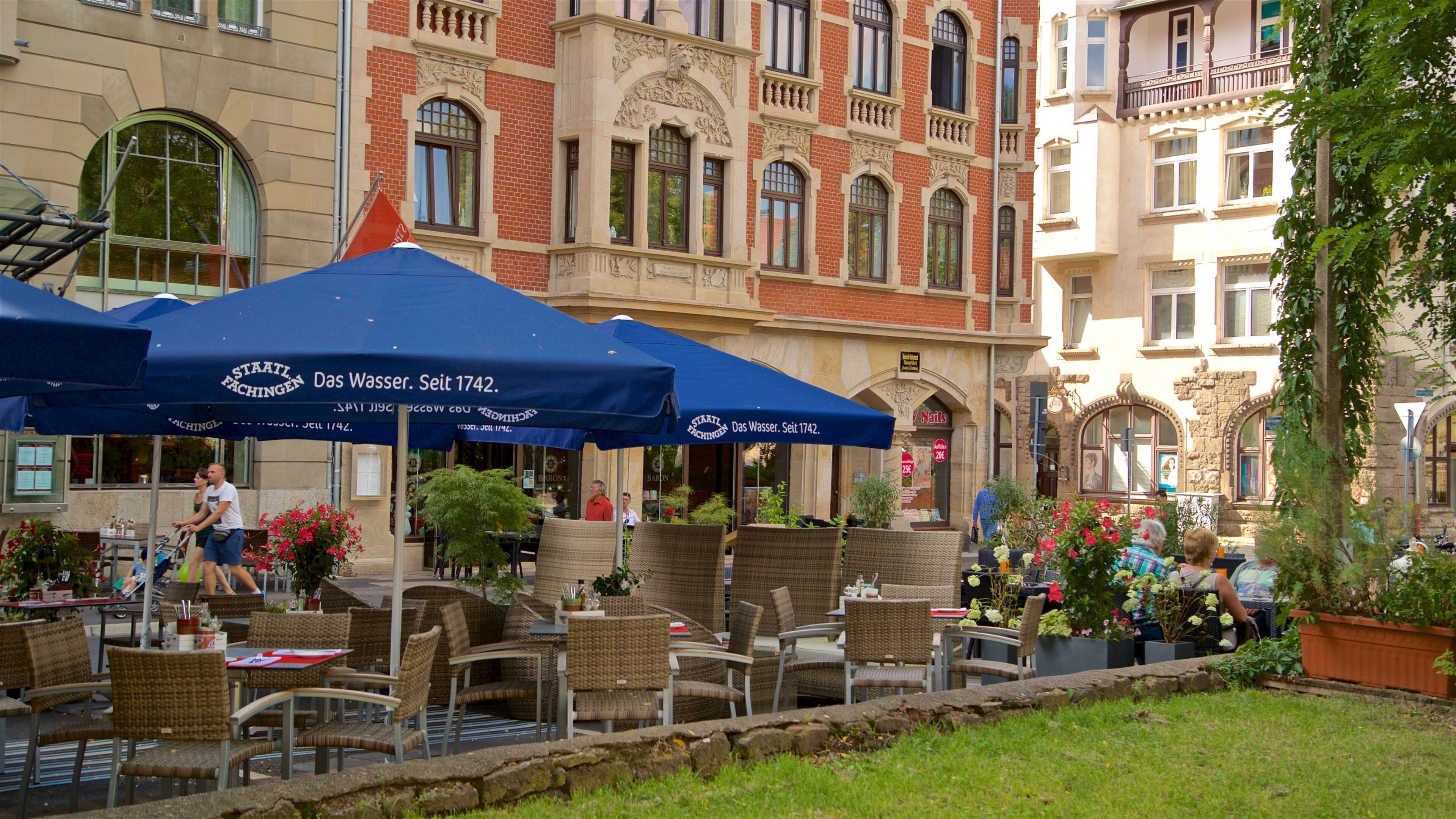 Outdoor seating with blue umbrellas, wicker chairs, and potted plants.