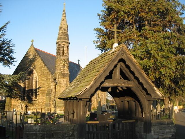 A church with a tall spire and a small chapel with a pointed roof.