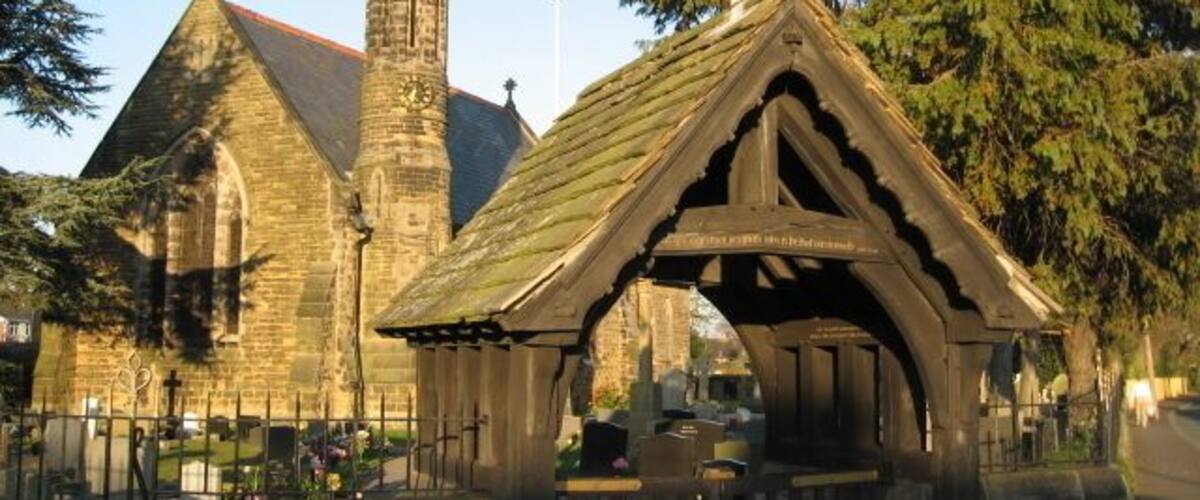 A church with a tall spire and a small chapel with a pointed roof.