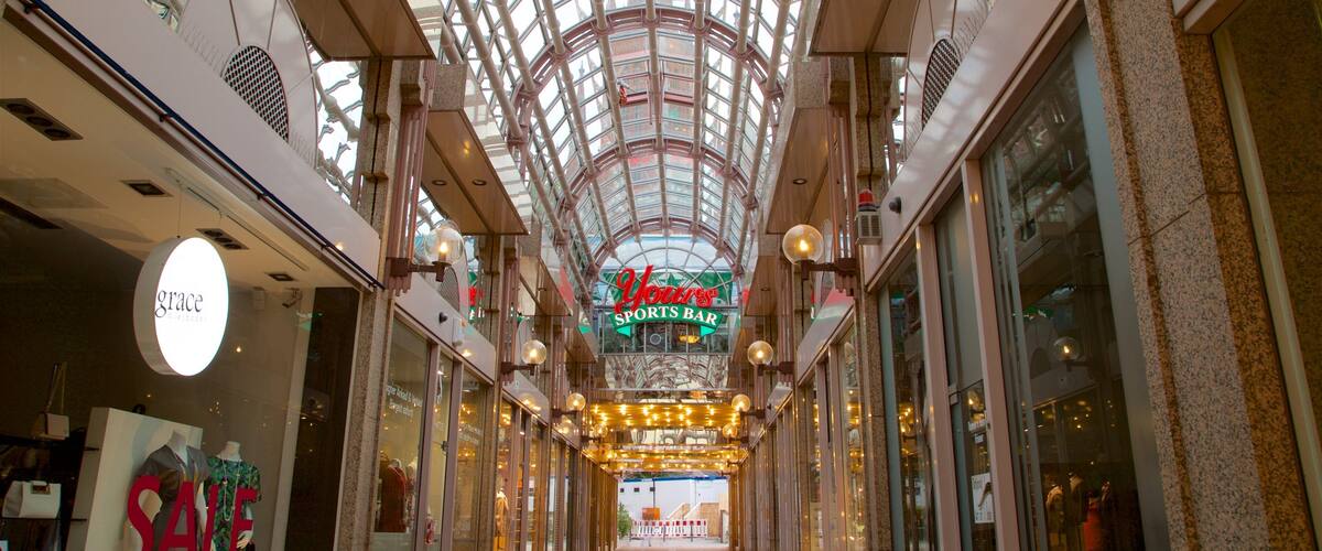 A shopping mall with a glass ceiling, a sports bar, and a sale sign.