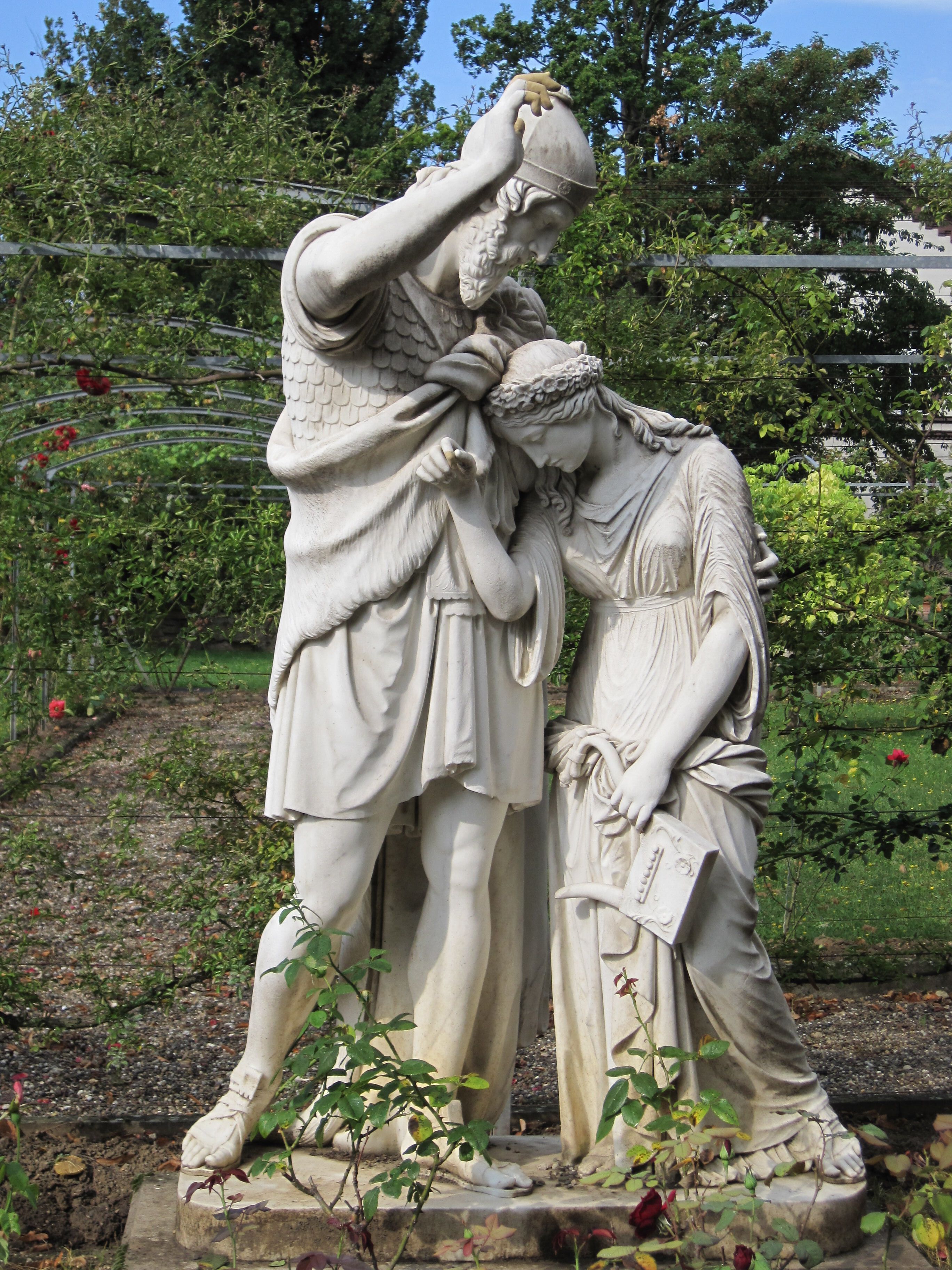 A classical statue of a man and a woman in a garden.