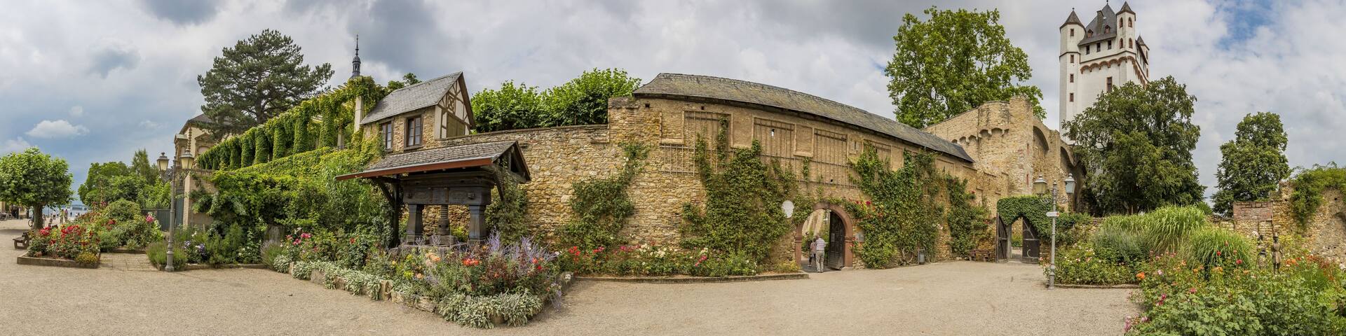A historic stone building with ivy, a small pavilion, and a tower.