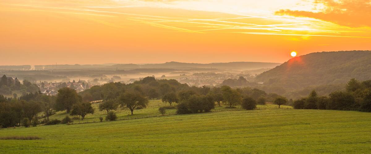 A sunset over a valley with a town in the distance.