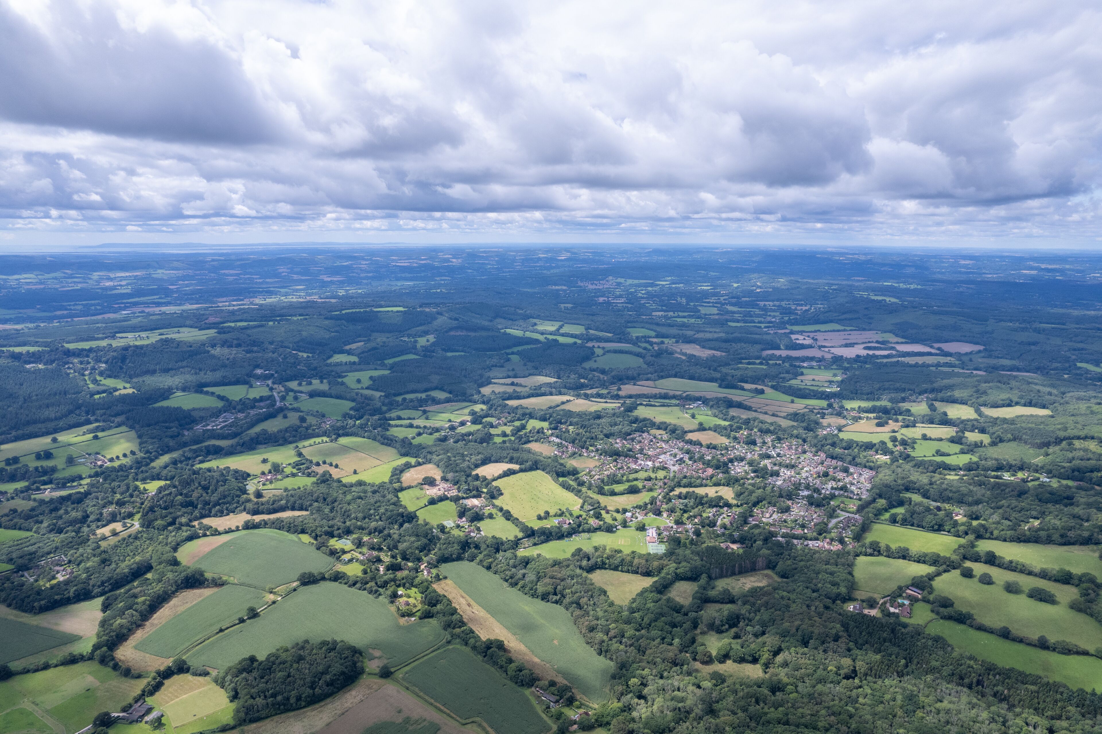 An aerial view of a rural landscape with fields, forests, and a small village.