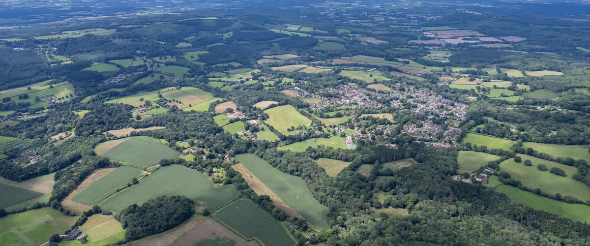 An aerial view of a rural landscape with fields, forests, and a small village.