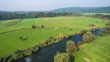 A river winding through a lush green valley with rolling hills in the background.