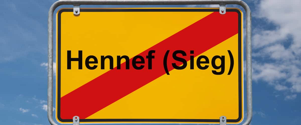 A road sign with the text "Hennef (Sieg)" against a blue sky with clouds.
