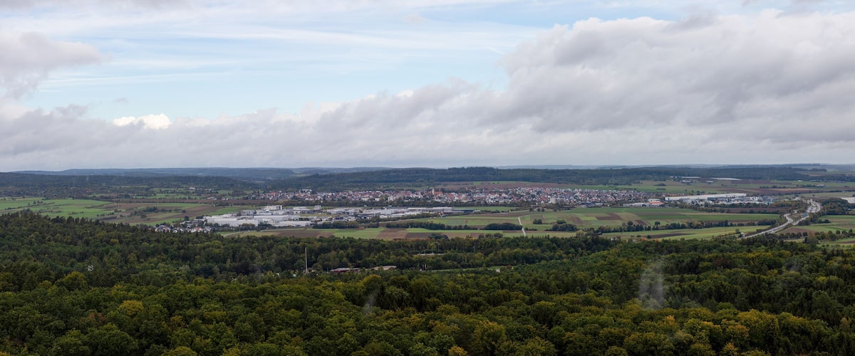 A town nestled in a valley with surrounding forested hills and fields.