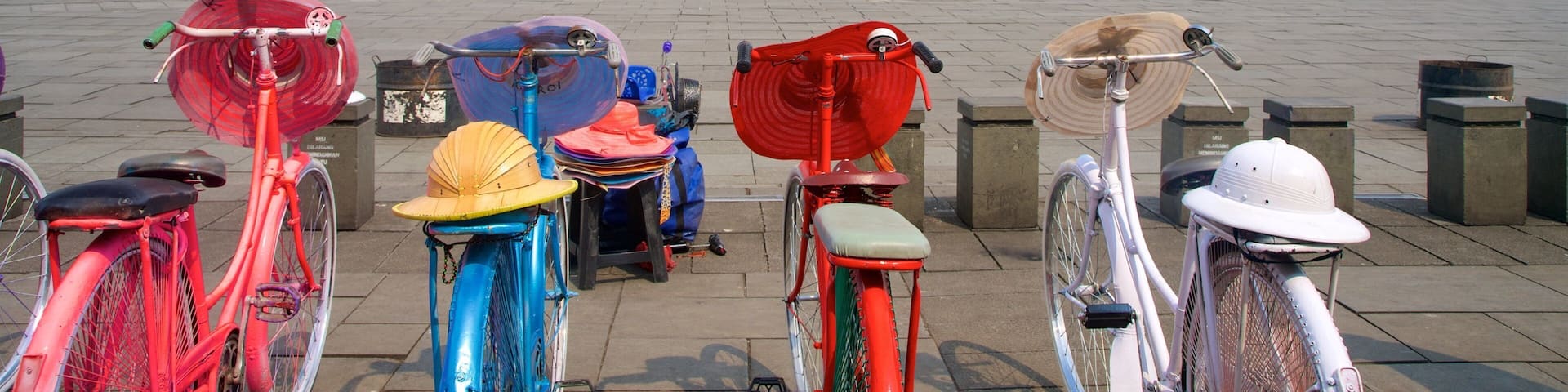 A row of colorful bicycles parked in front of a large white building with green shutters and a red roof.