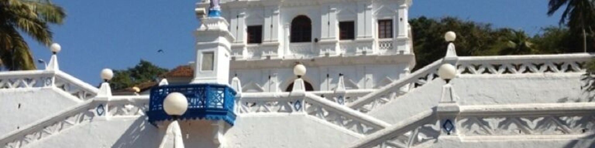 Un edificio de estilo colonial blanco con un campanario y una escalera que conduce a él.