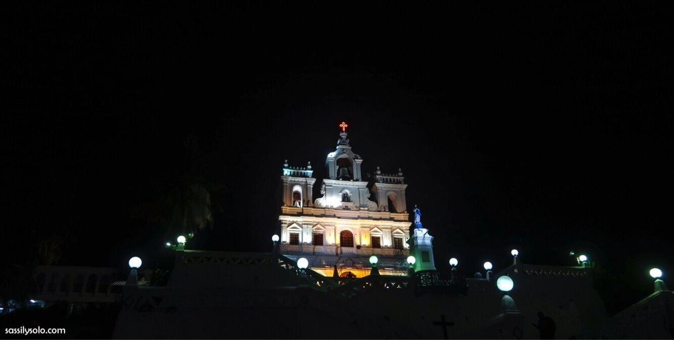 A lit-up church with a bell tower and crosses at the top.
