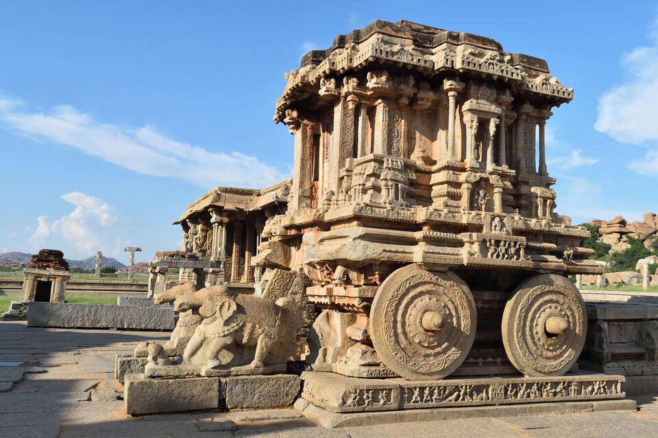 Una estructura de piedra antigua con intrincados grabados y ruedas grandes.