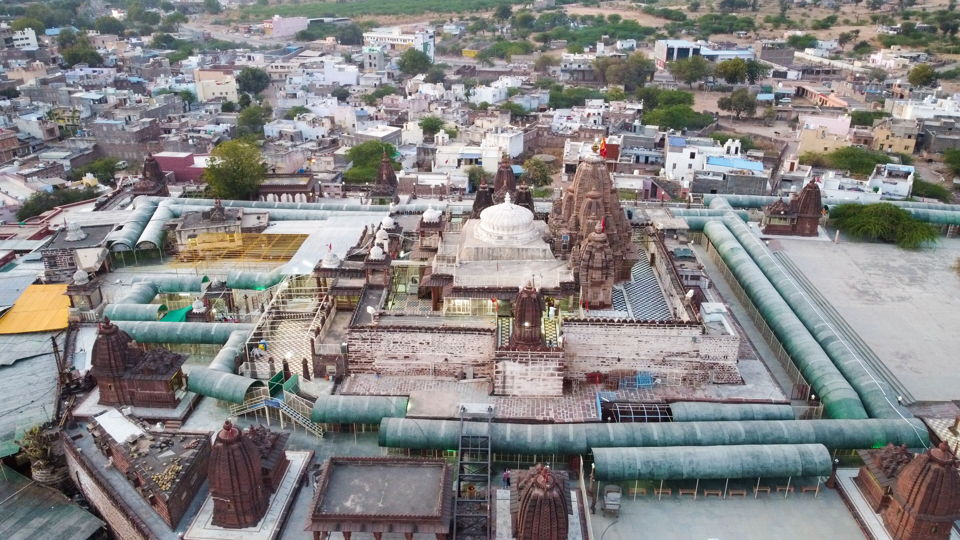 An aerial view of a temple complex with multiple domes and spires, surrounded by residential buildings.