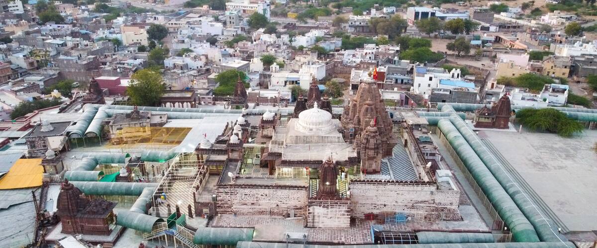 An aerial view of a temple complex with multiple domes and spires, surrounded by residential buildings.