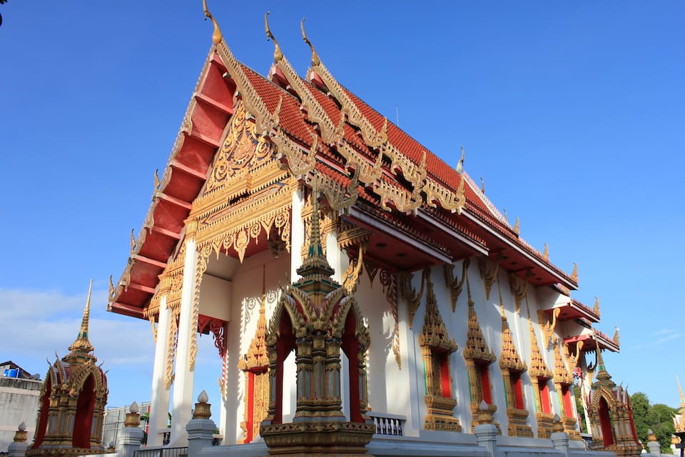 A traditional Thai temple with ornate golden decorations and a red roof.