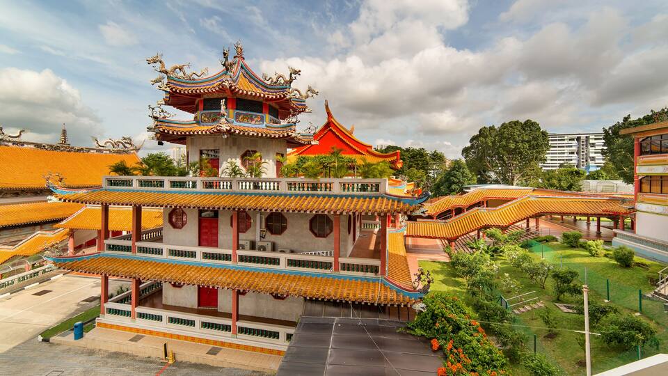A traditional multi-tiered temple with ornate roofs and a lush garden.