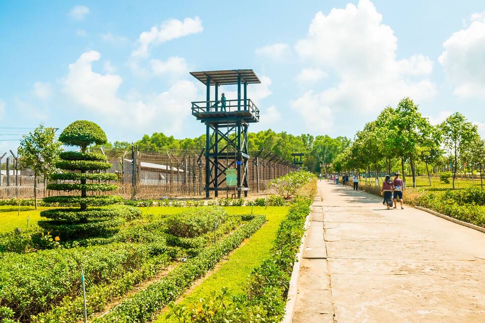 A park with a watchtower, neatly trimmed hedges, and a walking path.