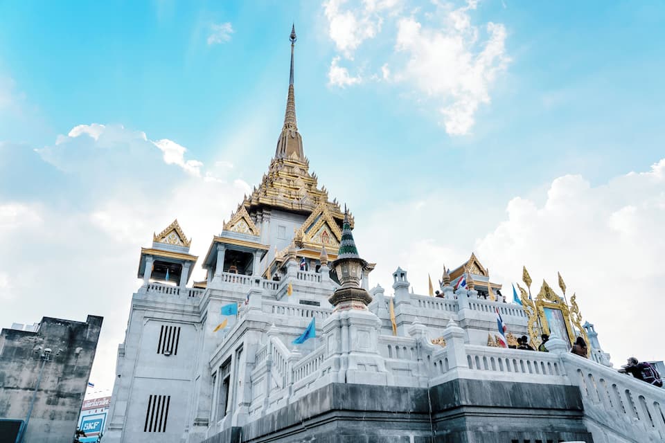 A grand temple with a tall spire, golden decorations, and flags.