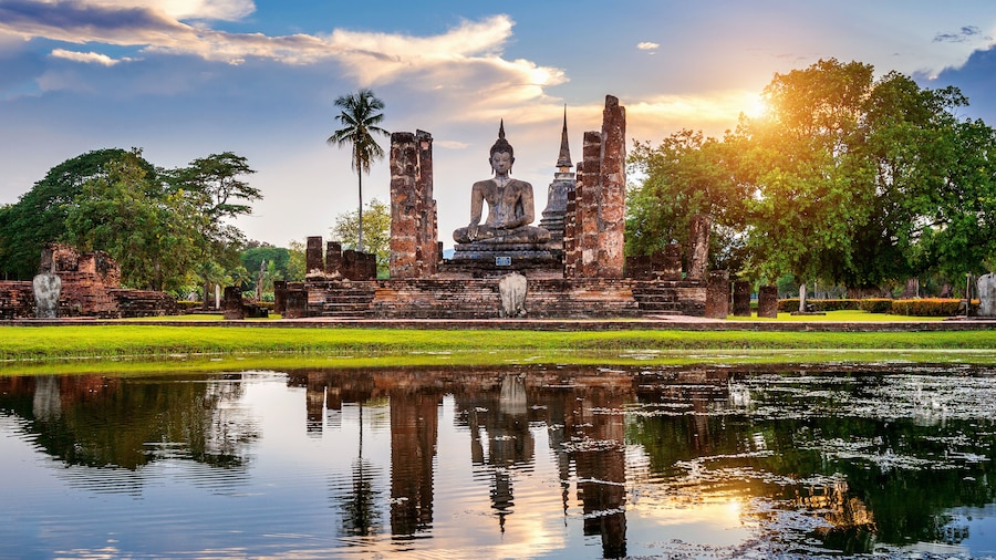 Buddha statue and Wat Mahathat Temple in the precinct of Sukhothai Historical Park, Wat Mahathat Temple is UNESCO World Heritage Site, Thailand.