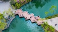 Aerial view of a zigzag stone bridge with visitors walking across green water at Slender West Lake in Yangzhou, Jiangsu Province, China. Scenic Chinese garden landscape with spring atmosphere
