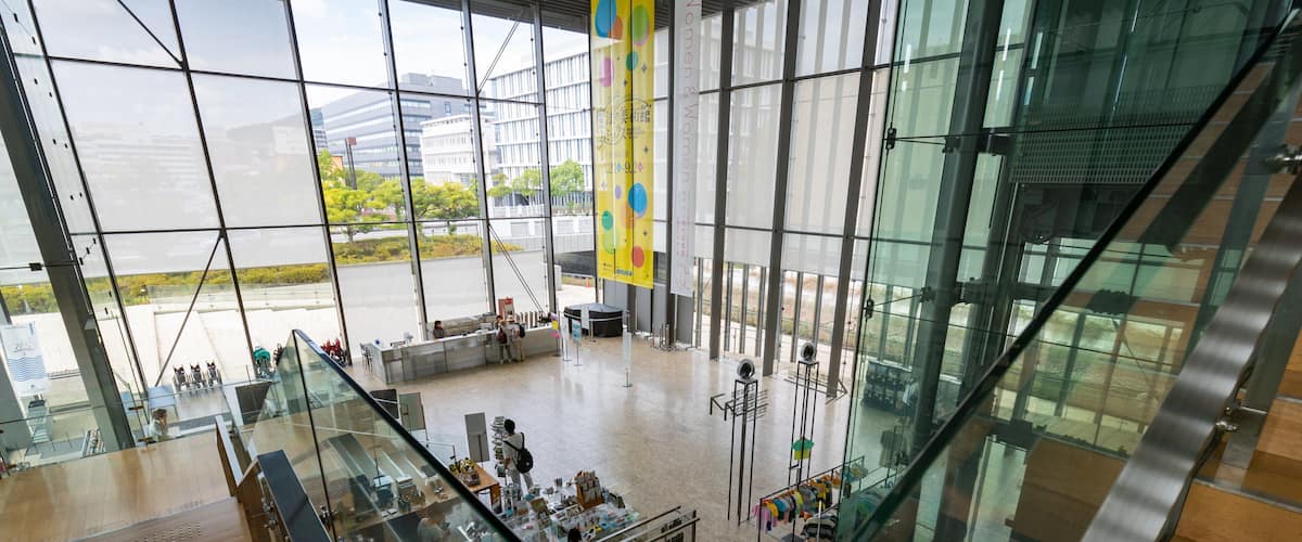A modern shopping mall with glass railings and a large glass wall.