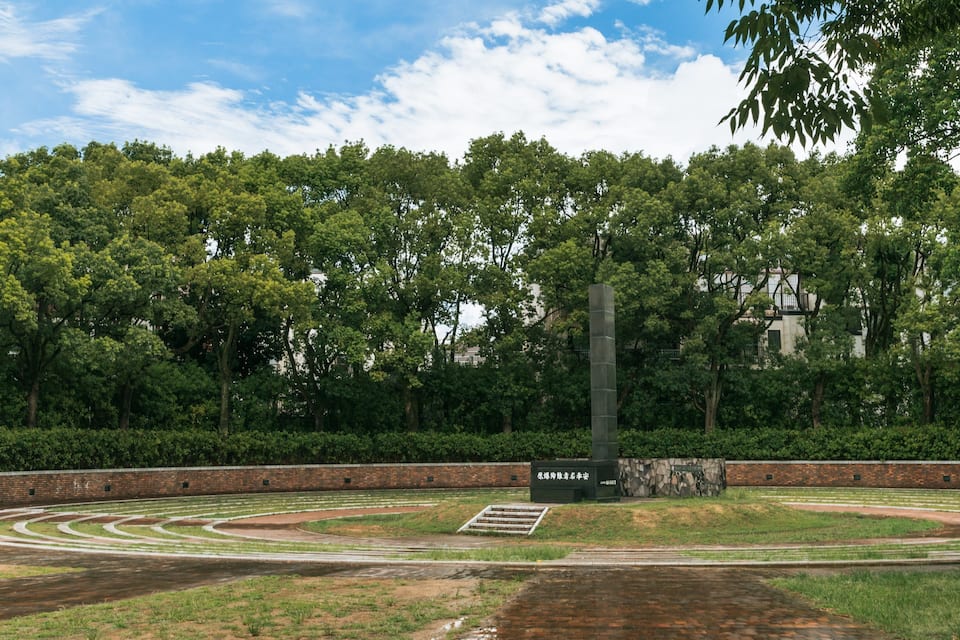 A park with a circular track, trees, and a brick wall.