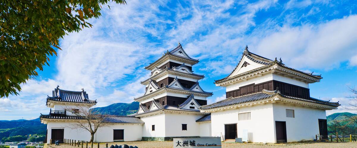 A traditional Japanese castle with multiple towers and a stone wall.