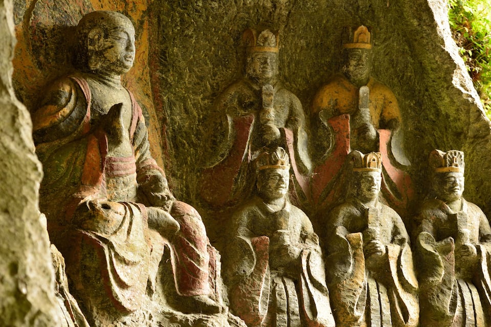 A series of ancient stone statues carved into a cliff face.