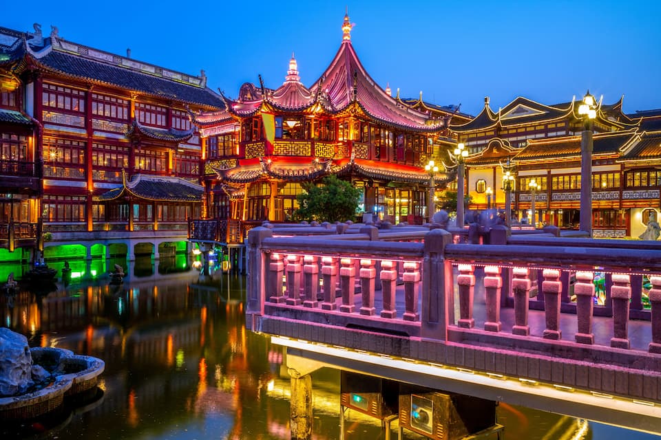 Un edificio tradicional chino con arquitectura ornamentada, un puente y un reflejo en el agua.