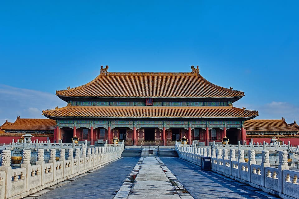 A traditional Chinese building with a tiled roof and a long, straight pathway leading to it.