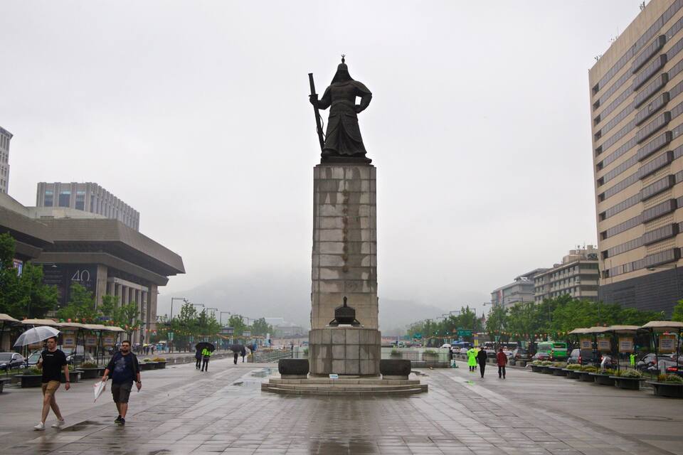 Uma estátua em uma praça rodeada por edifícios modernos.